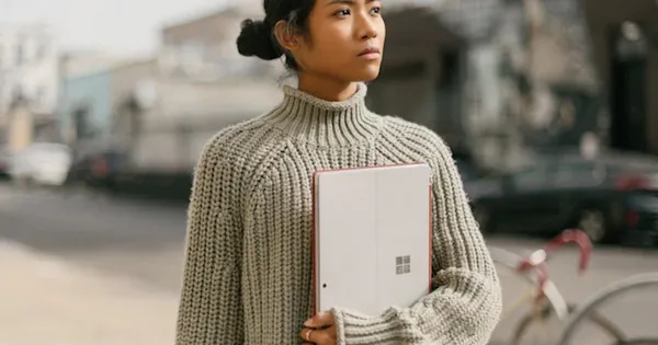 a woman standing on a sidewalk holding a laptop