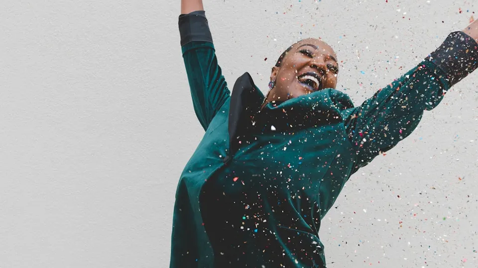 woman in green jacket raising her hands