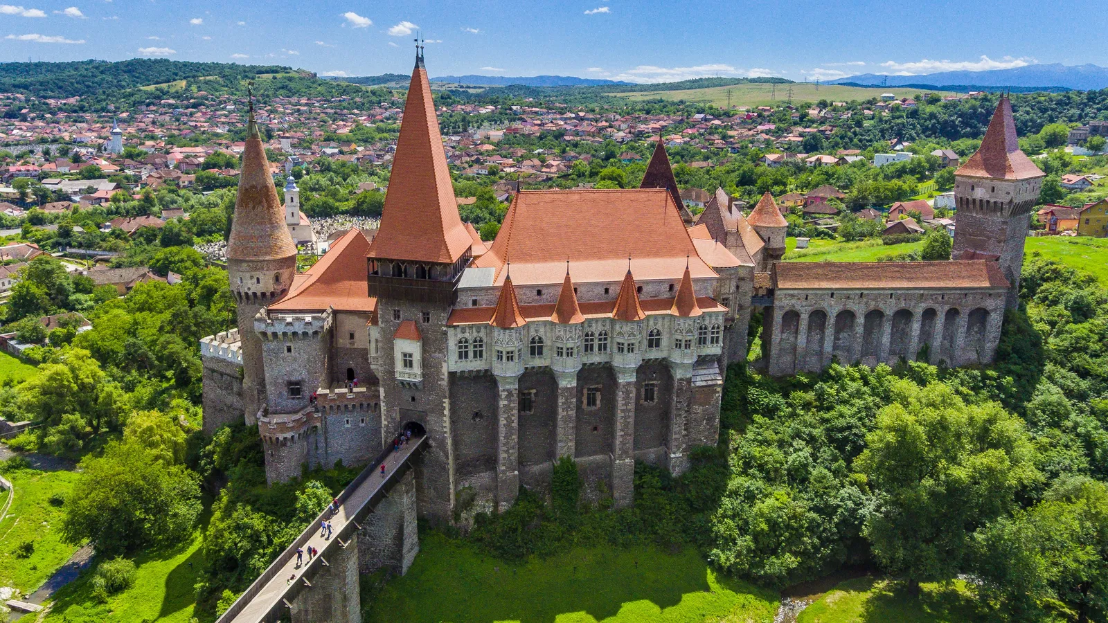 grey and brown concrete castle near green trees under blue sky during daytime