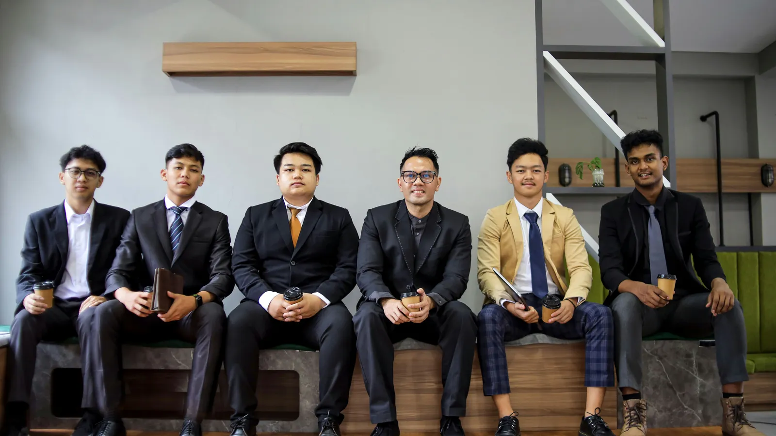 A group of young men in suits are posing.
